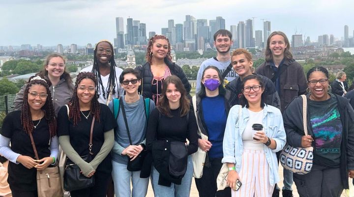 Students smile in front of the London cityscape