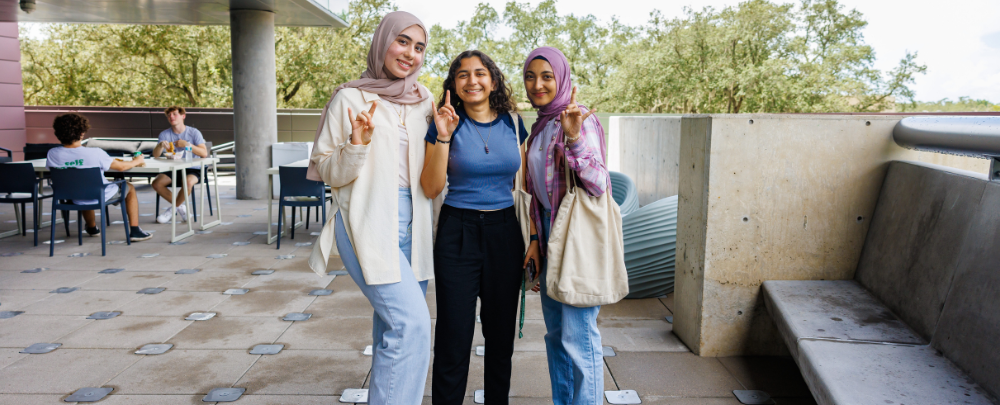 Three students smile on the second floor terrace.