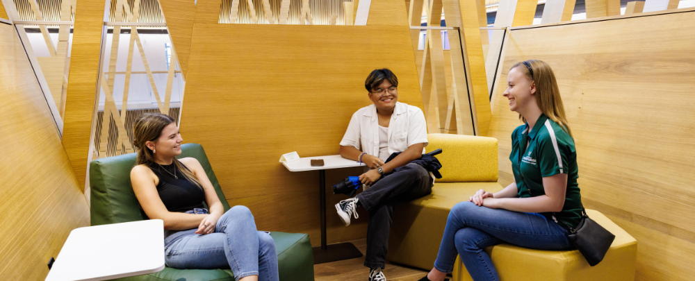 Three students talk in the learning lofts at the Honors building