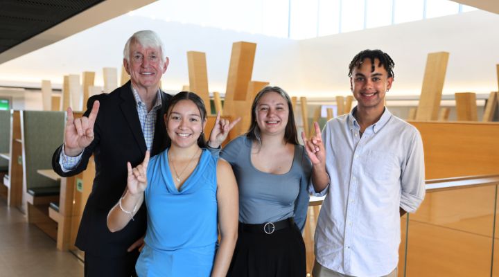 Wilcox scholars and Ralph Wilcox pose with the "Go Bulls" hand sign on the fifth floor of the Honors building.