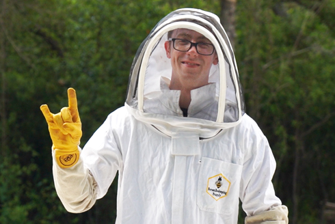 Kobe Phillips gives the go bulls hand gesture while standing outside in a bee keeping suit