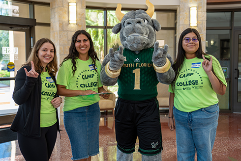 Three students pose with Rocky the Bull at USF's Sarasota-Manatee campus.