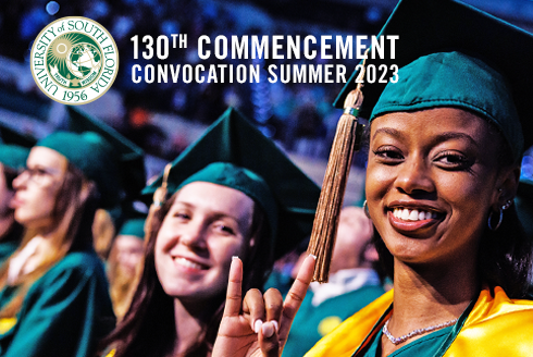 Students at commencement give go Bulls hand signal.