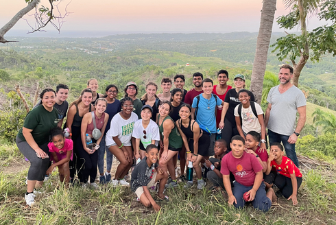 USF Judy Genshaft Honors College students and faculty pose with community members on a mountainside in the Dominican Republic