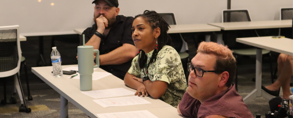 Grand challenge judges, Jon Dengler, Dr. Salim, and Kyle Roman sit a at table listening to student presentations.