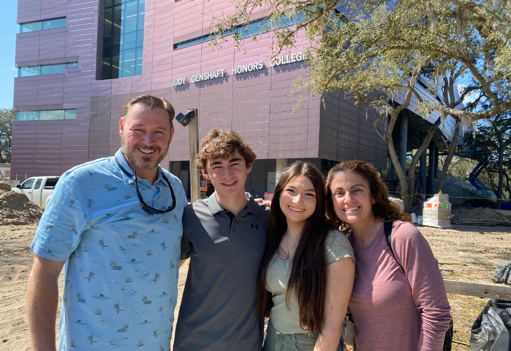 Dr. Rita Hurst smiles with family members in front of the new Judy Genshaft Honors College Building