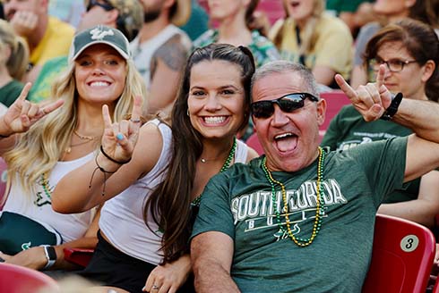 Group gives “Go Bulls” hand signal in the football stands.