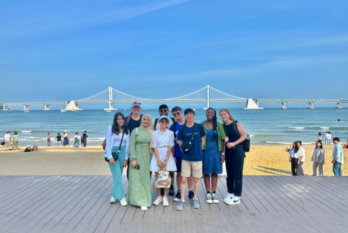 Honors students smile in South Korea standing on the beach.