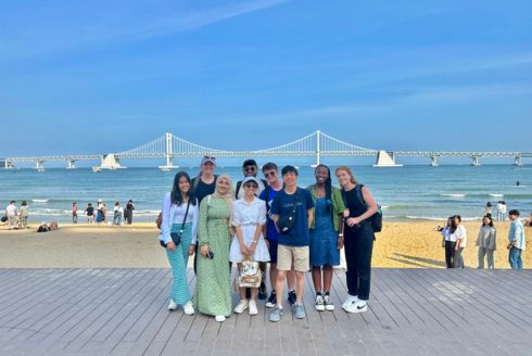 Honors students smile in South Korea standing on the beach. 