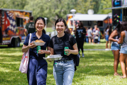 Students smile holding food and drinks at the Welcome Home Celebration