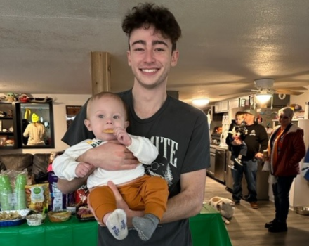 Honors student Aiden-Jaskolka Brown holding a young baby who was the recipient of an organ donation