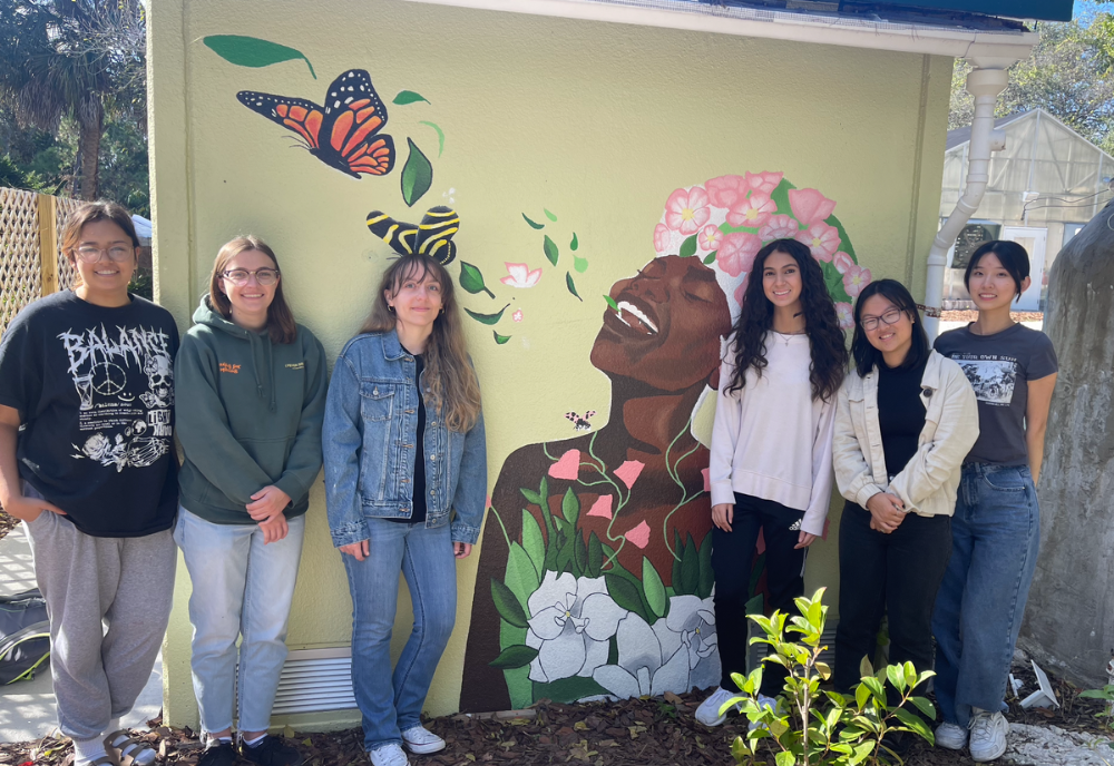 Honors students smile next to the completed breath of life mural. 