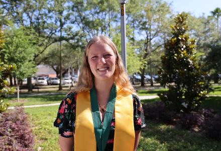 Honors Graduate Bethany Jowers smiles outside of the Judy Genshaft Honors College building