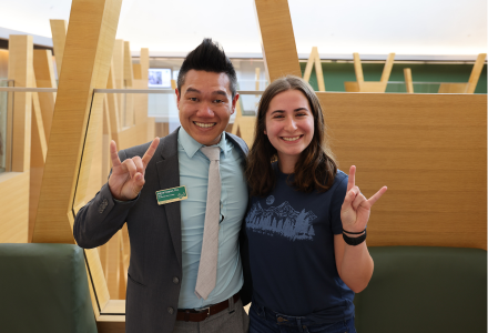 Dr. Andrew Hargrove and Morgan Mathews pose while making "Go Bulls" signs with their hands.