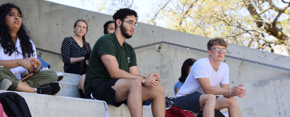 Multiple students listen to a lecture on the stairs of the Judy Genshaft Honors College as part of the 2024 USF Climate Teach-In