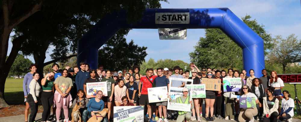 A large group of students from various student environmental organizations pose for a large group photo in front of the starting line at the Climate Teach-In 5k for climate starting line