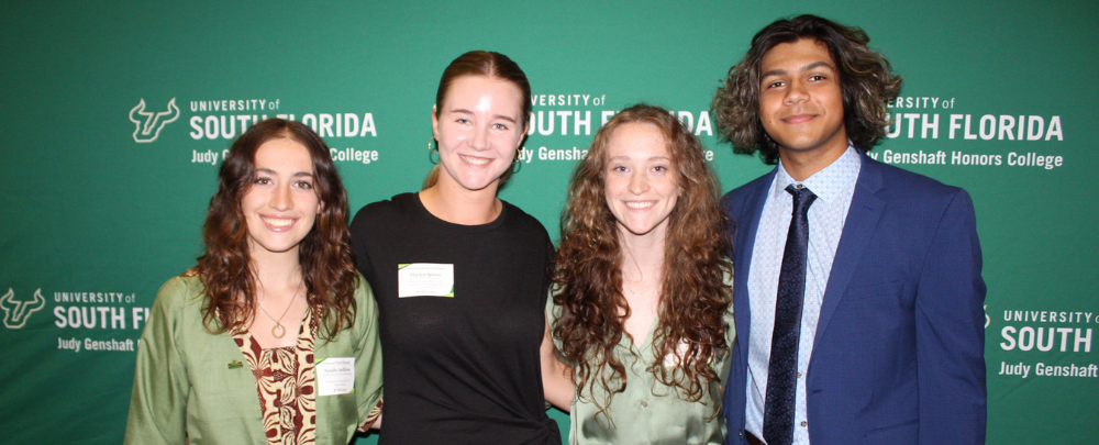 Daelyn Quinn and three other National Merit Scholars pose in front of a University of South Florida backdrop.