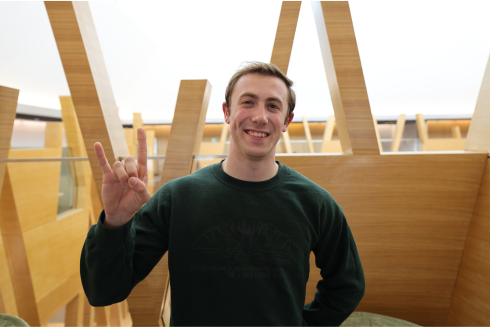 Judy Genshaft Honors College student Kobe Phillips poses in the Honors building while making a Go Bulls sign.