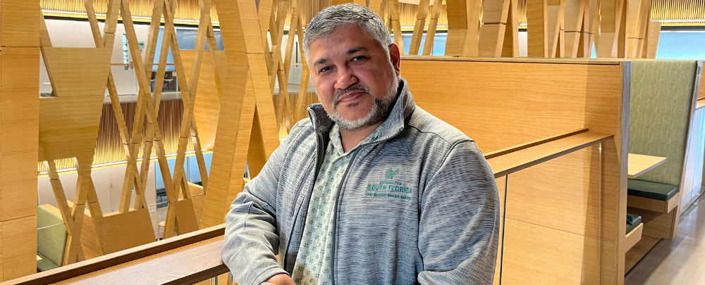 Honors Advisor Arnie Mejias smiles inside of the Judy Genshaft Honors College