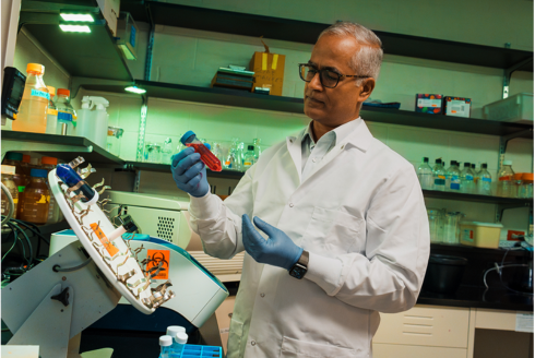 USF researcher holds a vial with red fluid.
