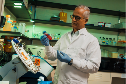 USF researcher holds a vial with red fluid. 