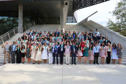 Spring 2025 USF Judy Genshaft Honors College Graduates pose for a group photo on the outdoor amphitheater stairs.