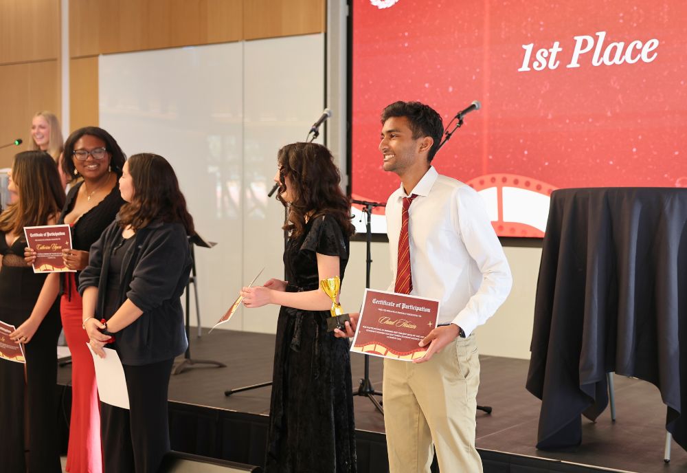 Honors Got Talent 2025 winner, Chad Hosein, posing with his certificate and trophy at the front of the atrium. 