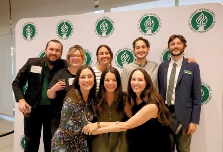 A group of Honors alumni and Grace Beck pose in front of a USF Honors College backdrop