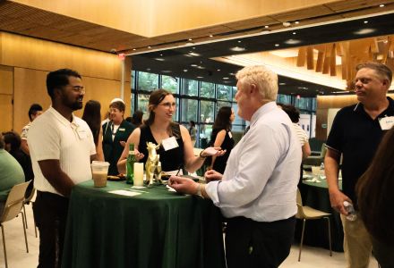 Honors alumni chat at a high-top table in the Honors forum.