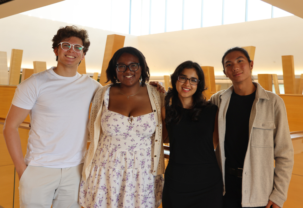 USF Honors students Ghali Omar Boutaib, Catherine Ugwu, Serena Bhaskar, and Rysun Chu smile on pose inside the Judy Genshaft Honors College building.