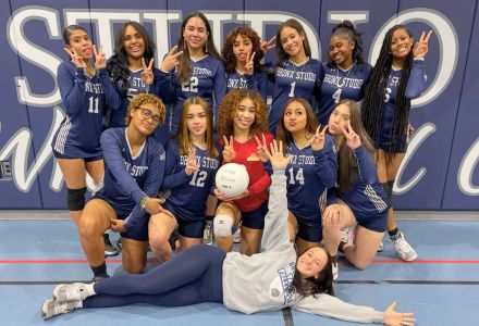 Carly Durgin lies down posing in celebration with her high school volleyball team that she coached.