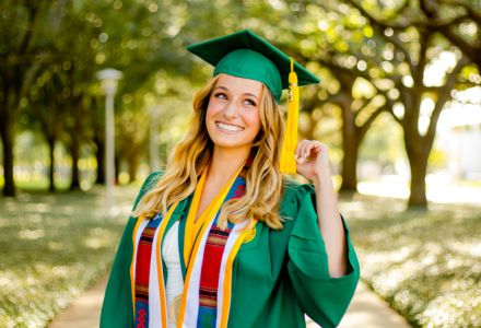 Carly Durgin posing in her USF bachelor's cap and gown and regalia on USF campus.