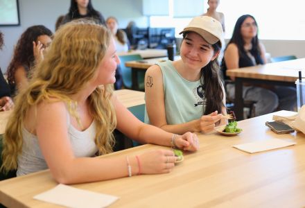 Two participants of the Climate Teach-In Sustainable Cooking demonstration talk while trying the chef's dish.