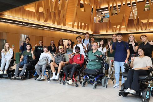 Instructor Kyle Romano poses with the students in his course with mobility equipment