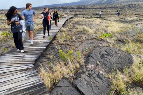 Honors students walk on boardwalk surrounded by dried lava in Hawaii.
