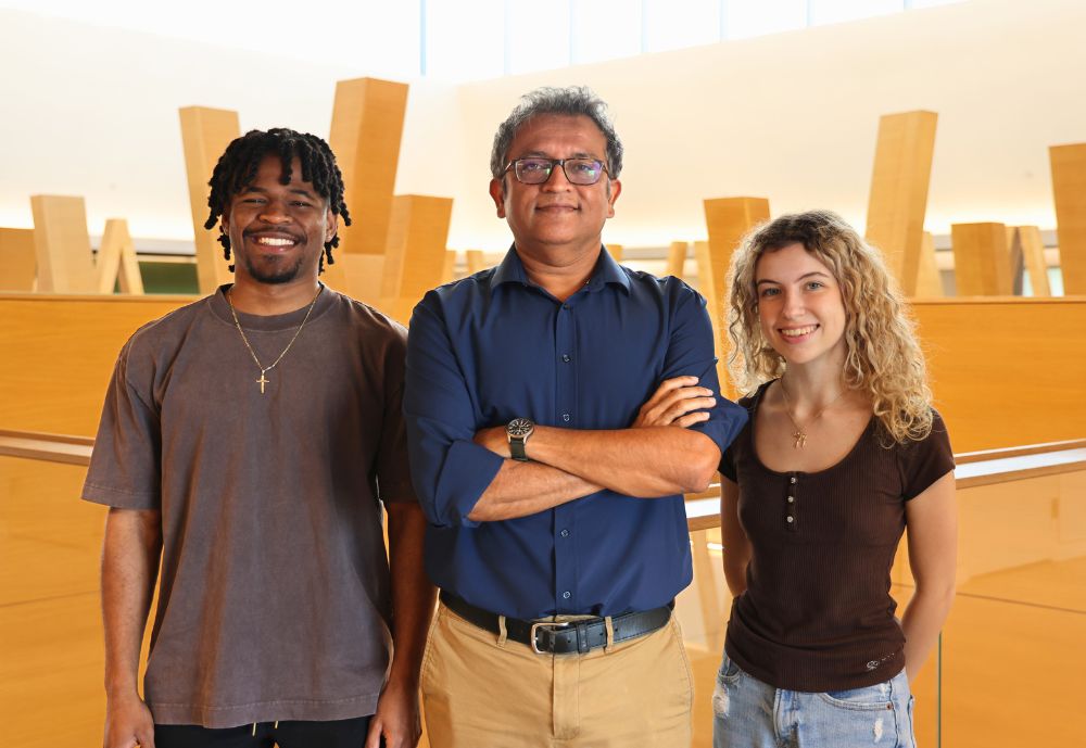 Daniel Anderson, Professor Deepak Singh, and Jenna Epright pose together on the fifth floor of the Honors building.