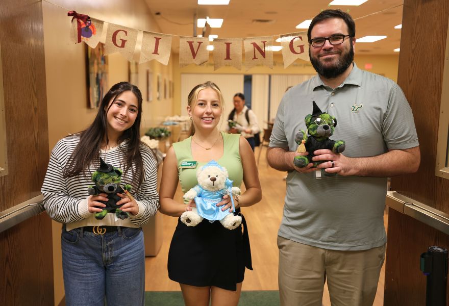 Marina Fizzuoglio, Alexandra Lewis, Dan Woods hold bears at friendsgiving