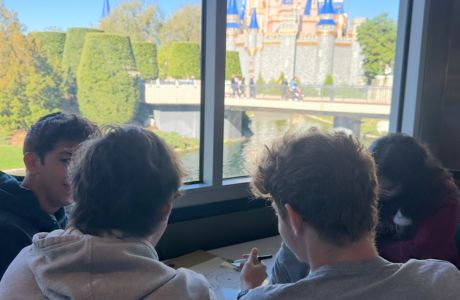 A group of LLC students meet to discuss their theme park design with a scenic view of the water and Disney’s Cinderella castle. Their design was a “space pirate” themed park.