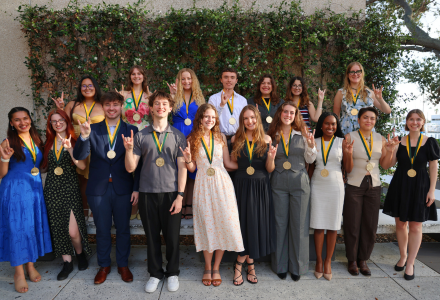 Honors graduates from USF's St. Petersburg campus pose while making Go Bulls signs.