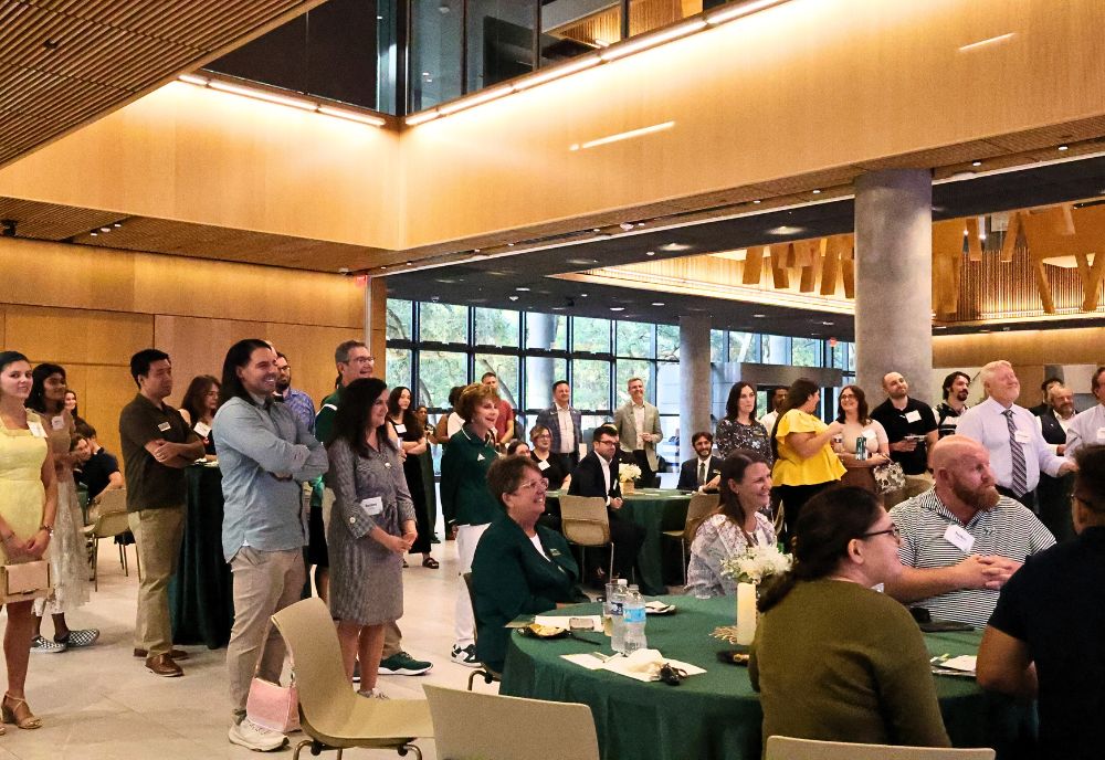 Honors alumni, Judy Genshaft, and Steve Greenbaum gather in the Honors forum and listen to opening remarks from Dean Adams at the Alumni Society Kickoff event.