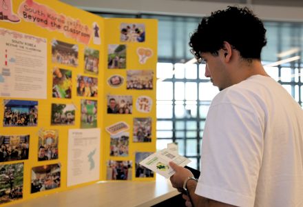 Honors student looks at South Korea poster with photos on it.