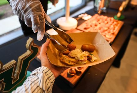 Tapas being placed with tongs in student's bowl.