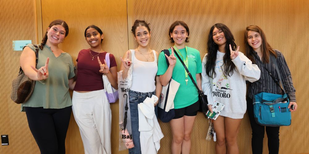 Honors students pose with the Go Bulls hand sign in the hallway of the second floor of the Honors building on their way to the next stop of the scavenger hunt.