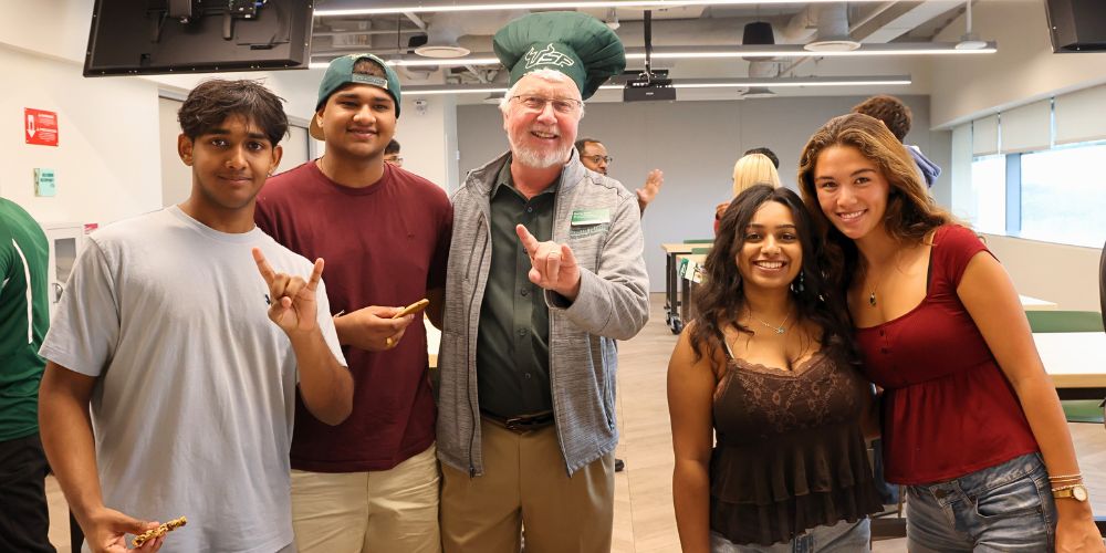 Honors students pose with Dean Charles Adams (in a USF chef hat) and cookies in the fifth floor Food and Culture studio in the Honors building.