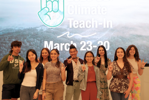 Student organizers from the 2026 USF Climate Teach-In pose while making Go Bulls signs in front of a Climate Teach-In graphic.