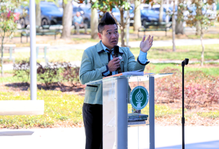 Judy Genshaft Honors College Professor Andrew Hargrove stands behing an outdoor podium while giving How to Save a Planet public lecture. 