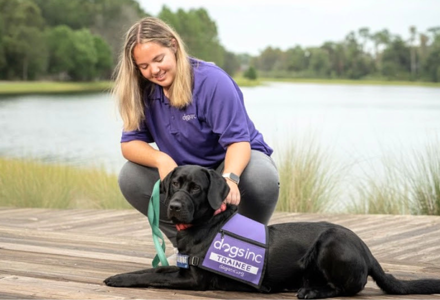 Alexa and the dog she trained (black lab)