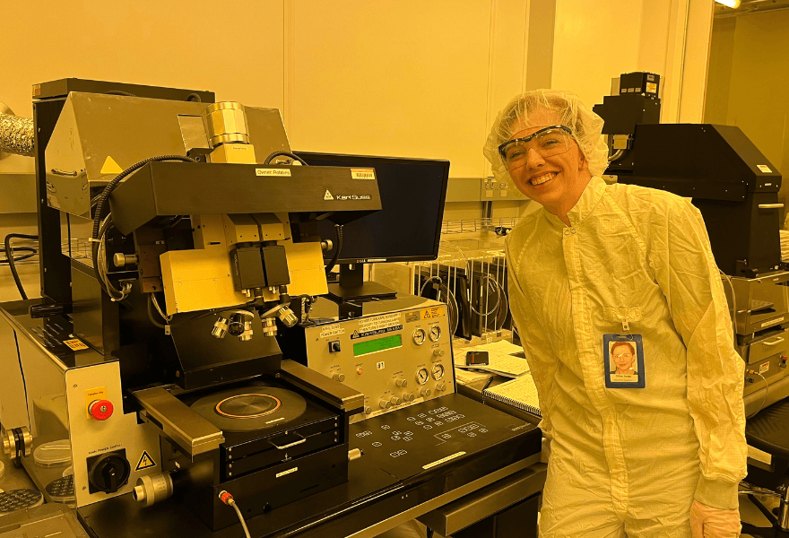 Chloe Jones poses next to spectroscopy machine at her REU at University of Texas at Dallas