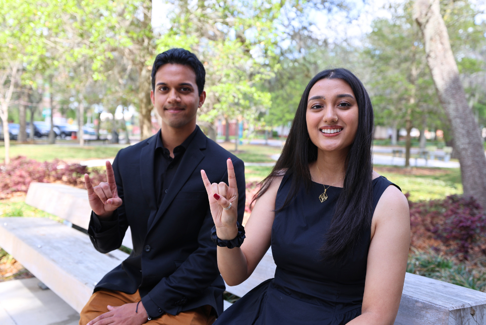 Caleb Fernandes and Diya Upadhyaya show their bull spirit on a bench outside the Judy Genshaft Honors College