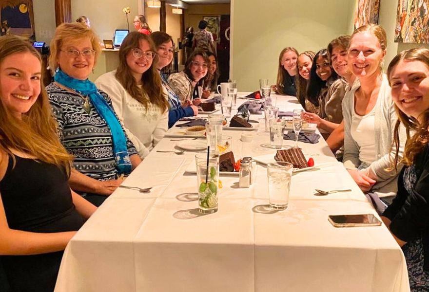 students, Dr. Brooke Hansen, and Audra Santerre at a large dinner table